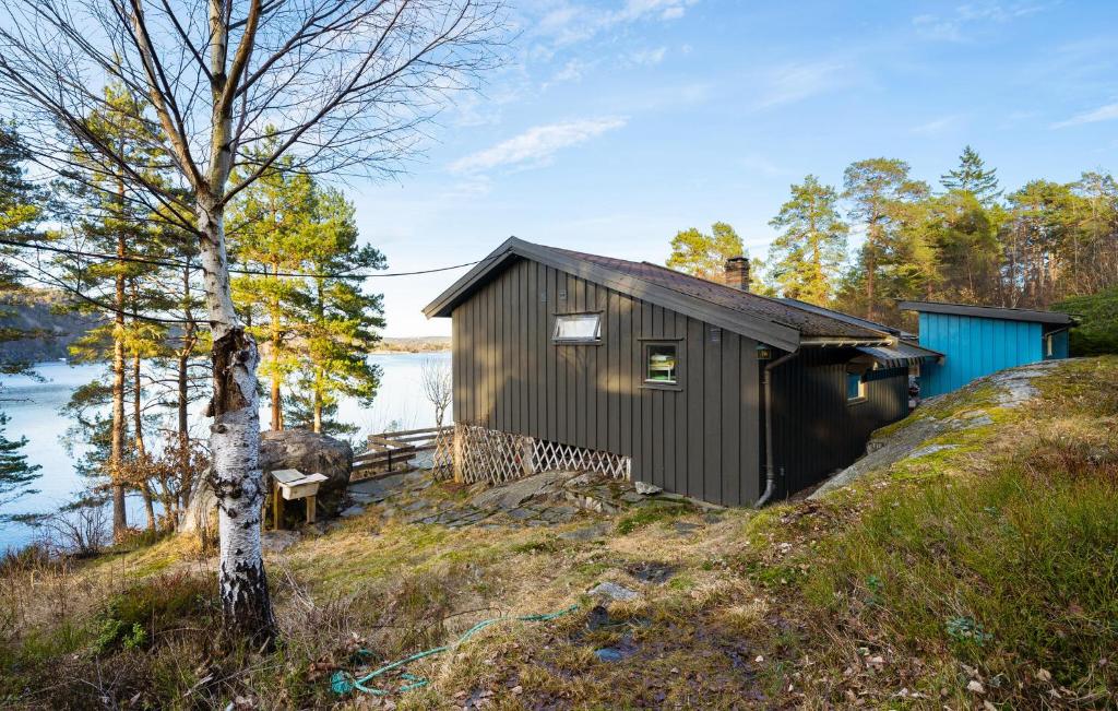 a small shack on the side of a hill next to a lake at Nice Home In Risør With House Sea View in Risør