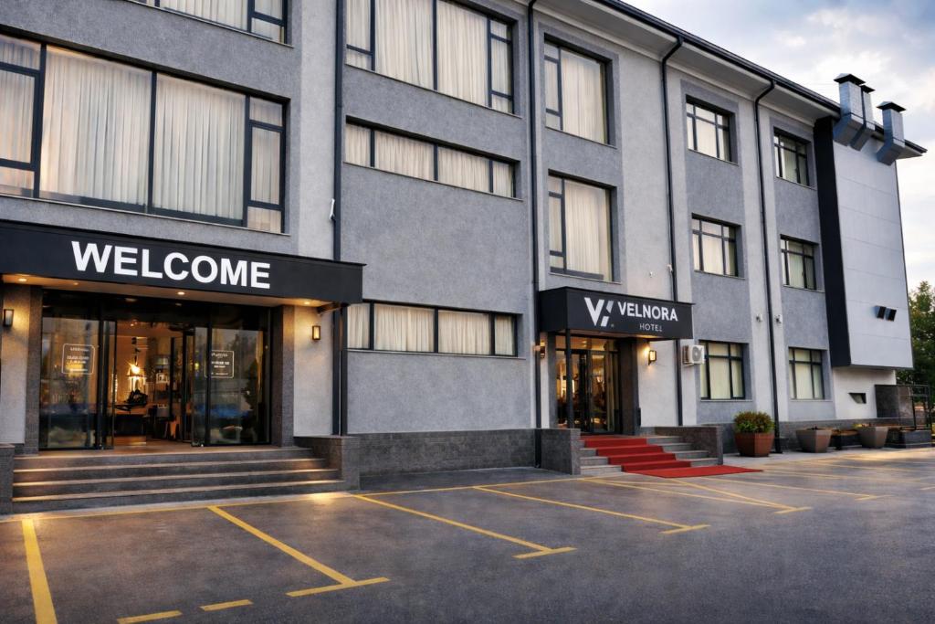 a building with a welcome sign in a parking lot at Velnora Hotel in Tashkent