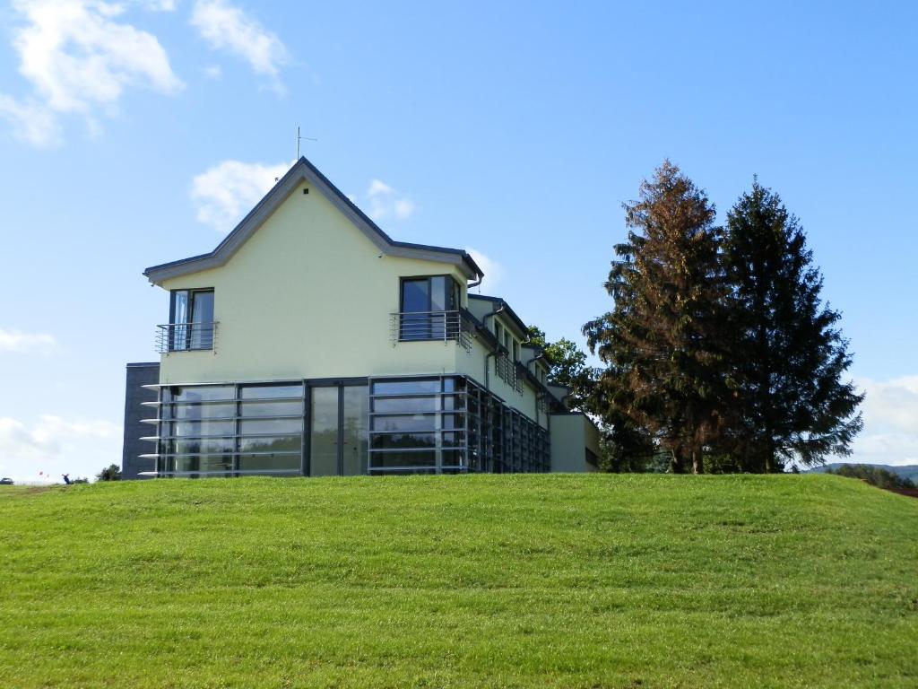 Golf Resort Česká Lípa في نوفي بور: منزل على تلة مع عشب أخضر