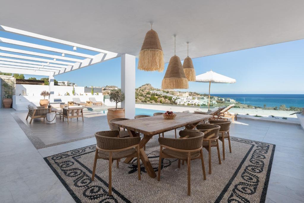 a dining room with a table and chairs and the ocean at Villa Aristoteles in Lindos