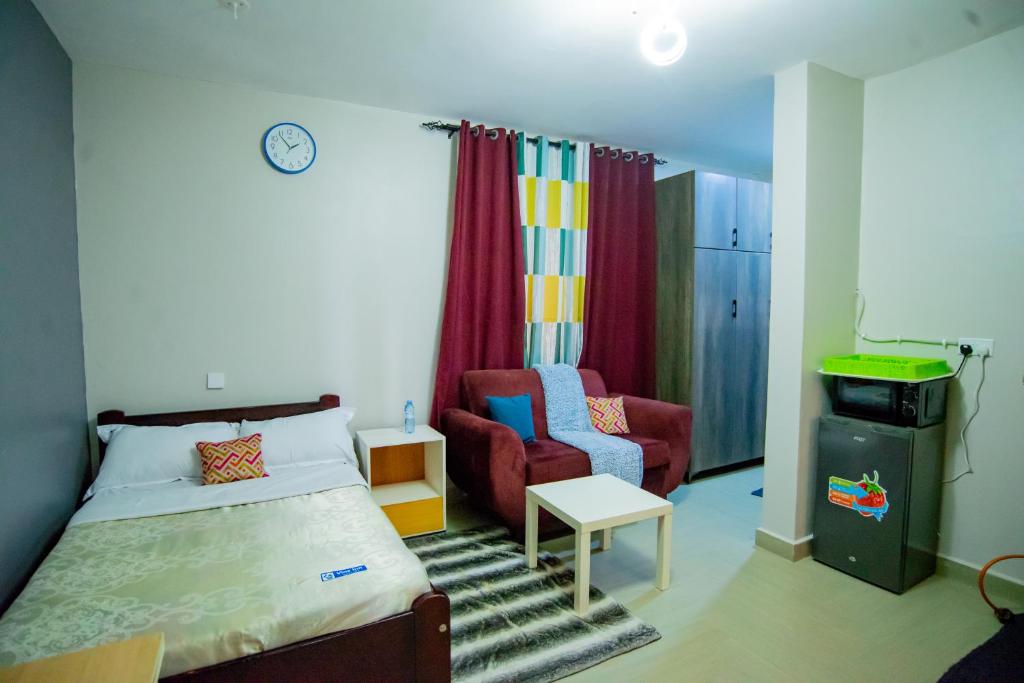 a bedroom with a bed and a couch and a chair at Vine Suites Mbarara - 1 Bed Studio Apartment Near LDC & City Centre - Quiet & Convenient in Mbarara