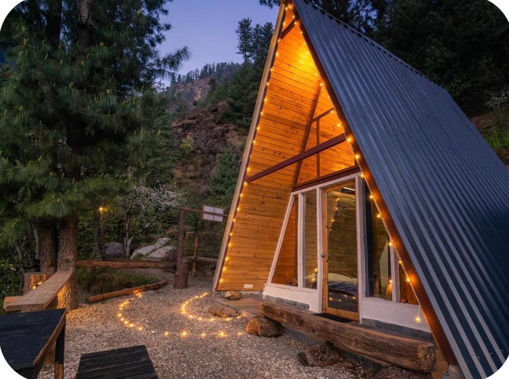a small house with a large window and lights at Tri peak Cottage in Jibhi