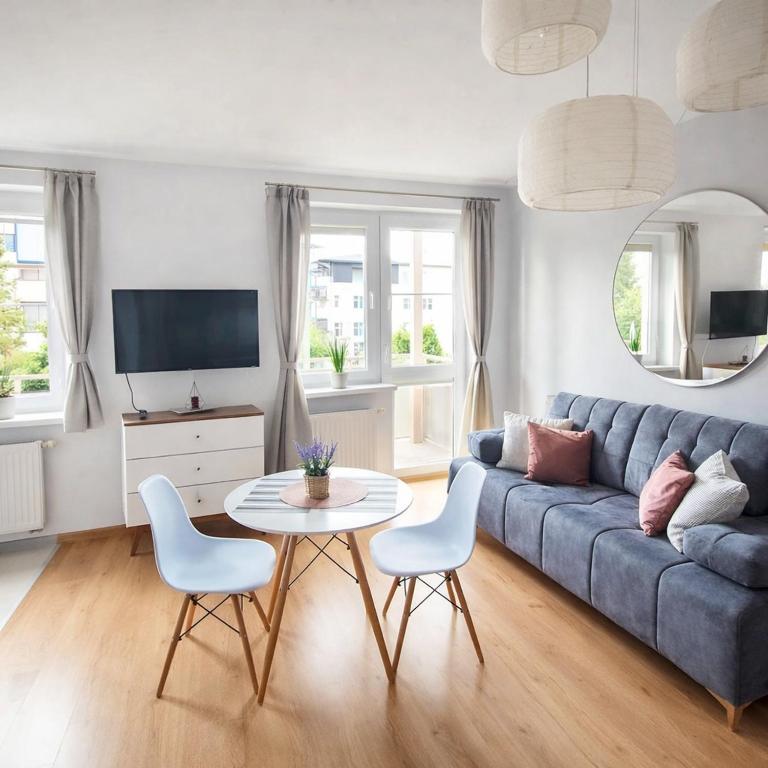 a living room with a blue couch and a table at Olly Apartament PARKING i BALKON Ciechocinek in Ciechocinek