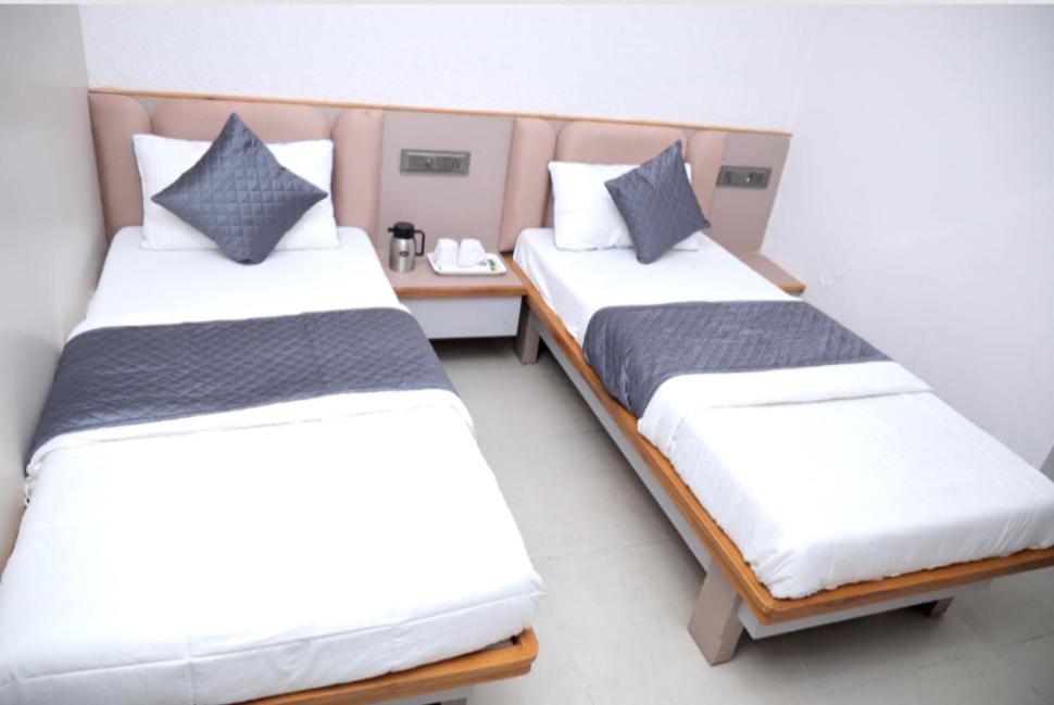 zwei Einzelbetten in einem Zimmer mit einem Tisch in der Unterkunft Hotel Excellency in Dīsa