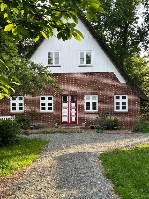 a red and white brick house with a red door at Haus Adele in Drochtersen