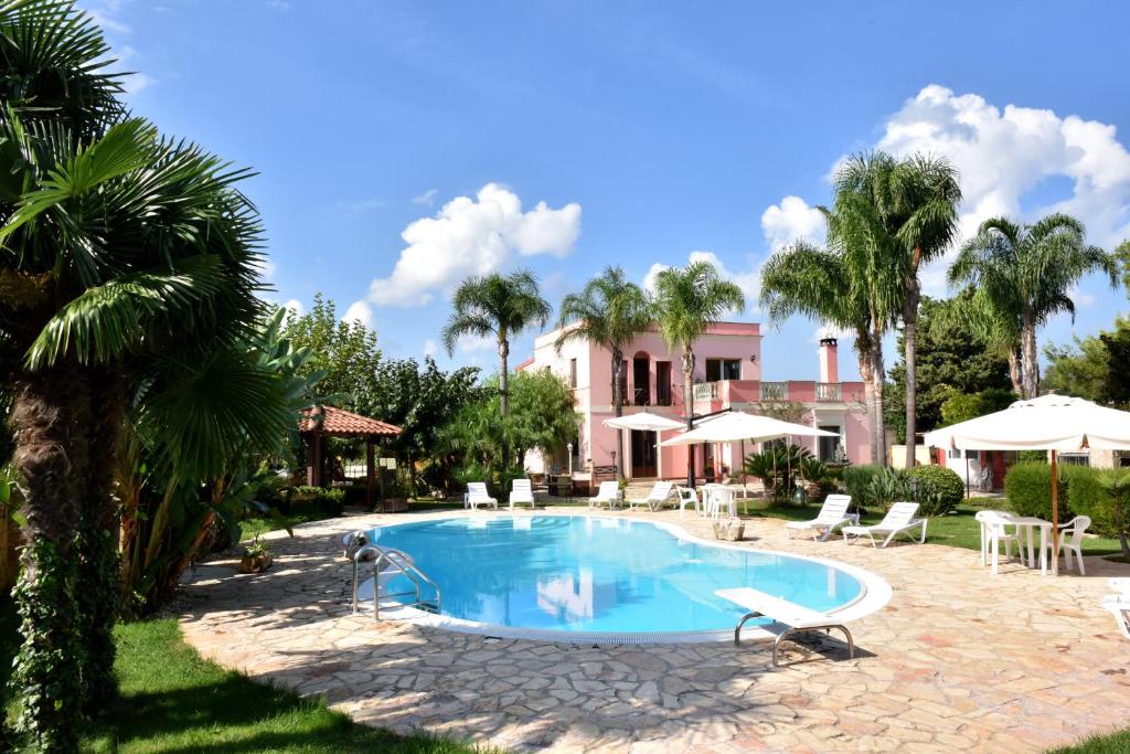a swimming pool in front of a house with palm trees at B&B Villa Anastasia Club in Mesagne