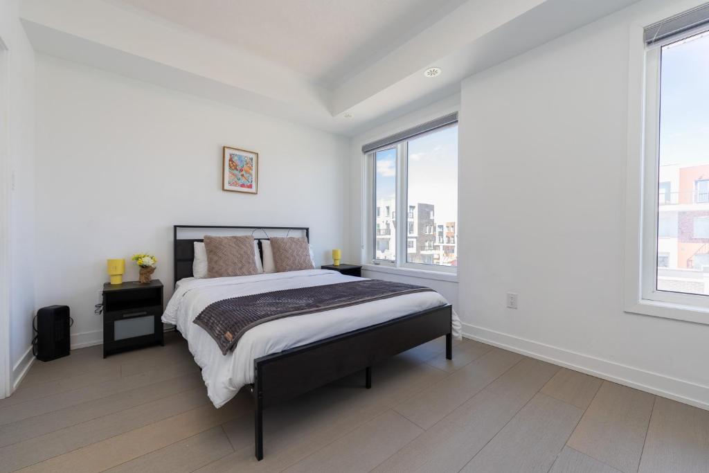 a white bedroom with a bed and two windows at Downsview Park Luxury Townhome near Yorkdale Transit in Toronto