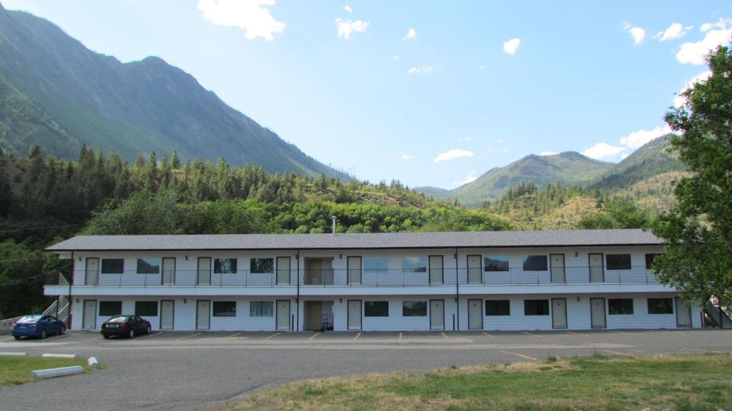 a large white building with mountains in the background at Retasket Lodge & RV Park in Lillooet