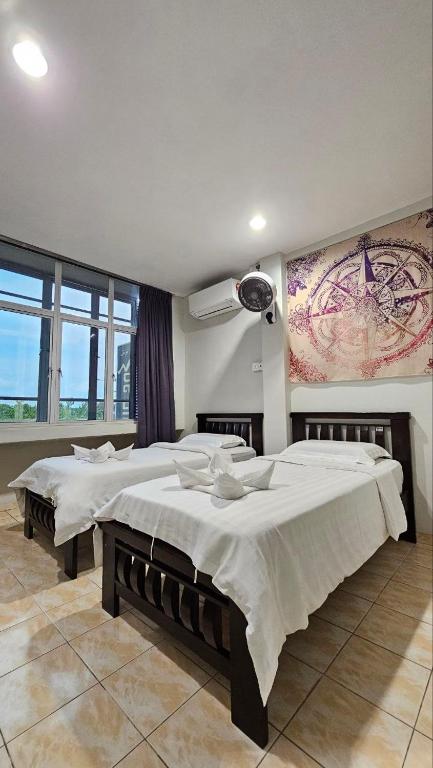 a bedroom with two beds and a painting on the wall at De Chukai Hotel in Kampong Kemaman