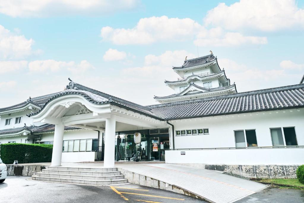 a white building with a tower in the background at Tabist Yuasa Castle Onsen Hotel in Yuasa