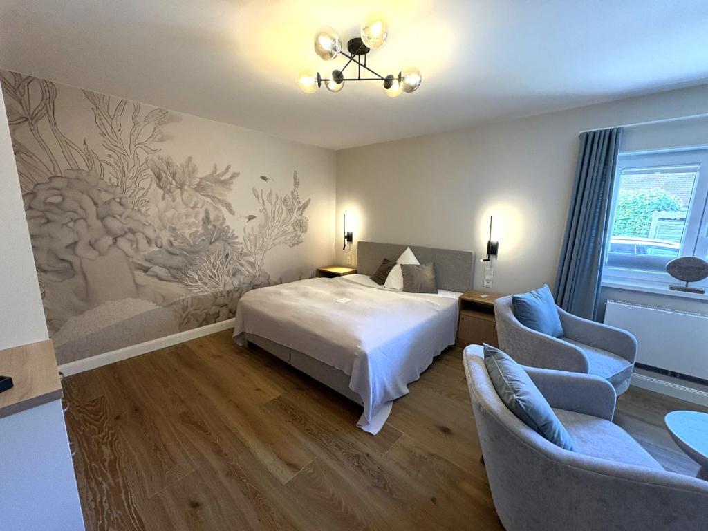a bedroom with a bed and two chairs at Boardinghouse Robbe in Westerland