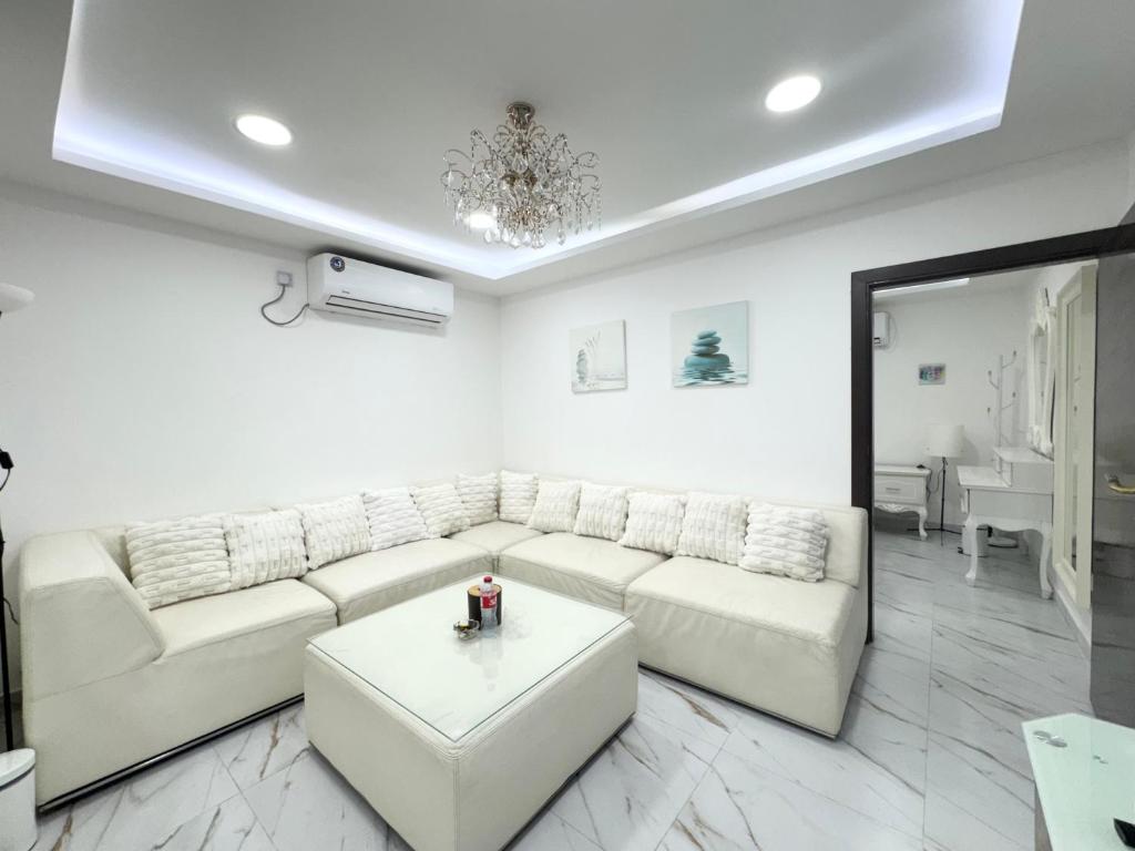 a white living room with a couch and a table at Velmora 1BR Apartment 13 in Abu Dhabi