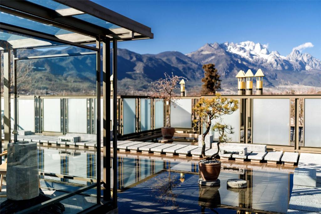 a resort with a pool and mountains in the background at Wumo Qinglu Snow Mountain Museum Hotel in Baisha