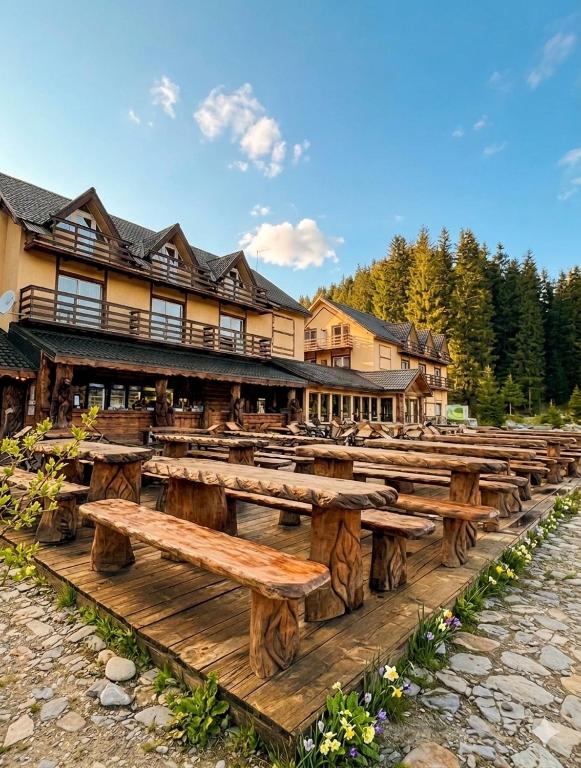 a row of wooden benches in front of a lodge at POARTA PADINA, statiunea Pestera-Padina, Bucegi in Moroeni