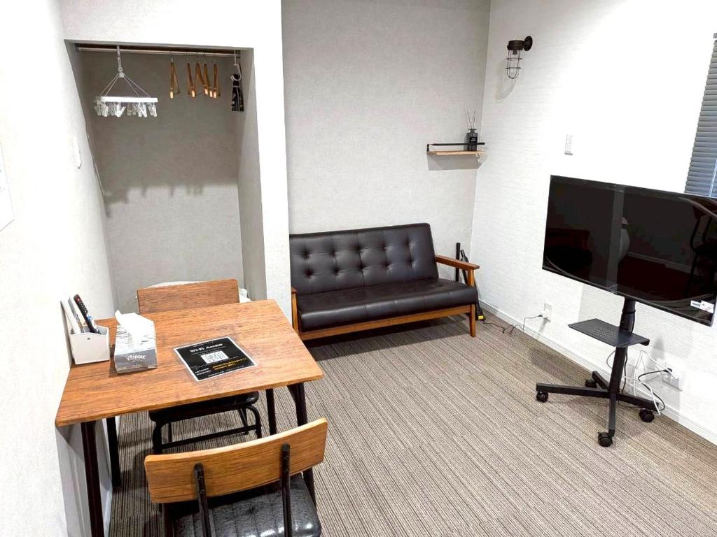 a living room with a couch and a table and a television at Room One in Aomori
