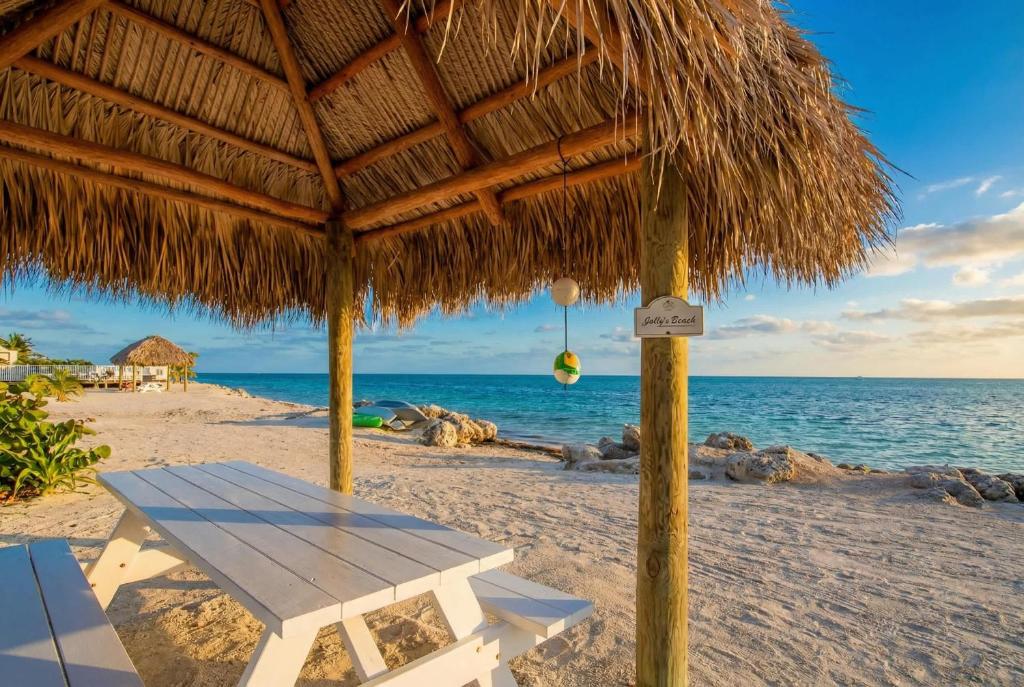 a straw umbrella on a beach with the ocean at Stylish Angler's Retreat, Poolside & Ocean Access #16 in Marathon