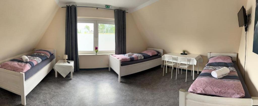 a room with two beds and a table and a window at Pension Highway - Bünde Carl Diem Straße 46 in Bünde