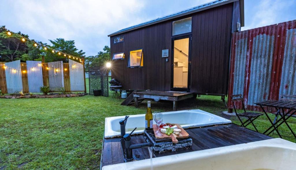 a tiny house with a table and a bottle of wine at Echidna by Tiny Away in Thoopara