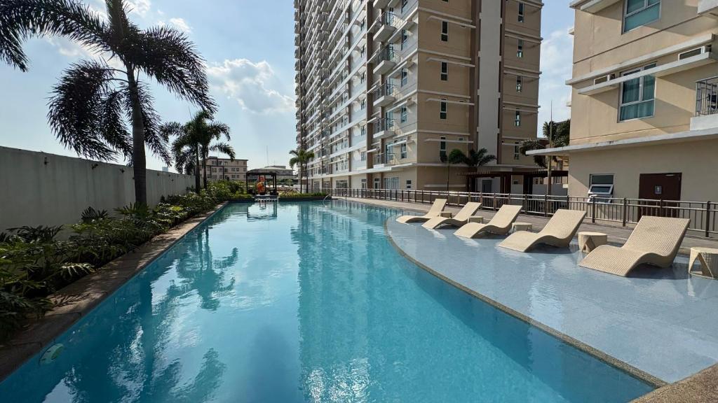 a swimming pool with lounge chairs and a building at Peppers Crib in Manila