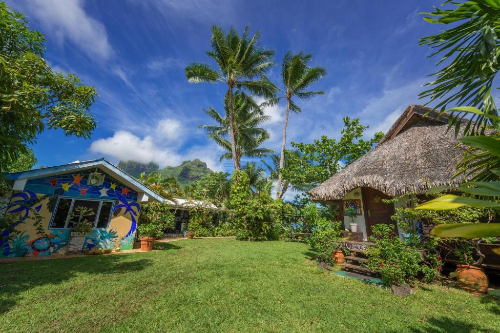 a house with a thatched roof and a yard at Bora Bora Bungalove in Bora Bora