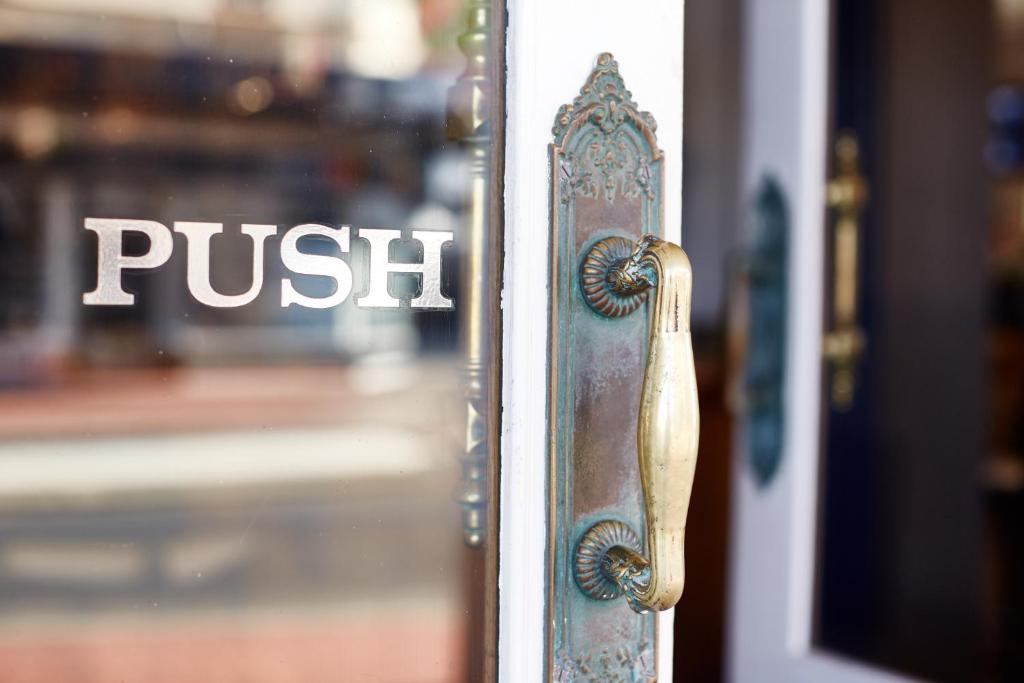 una manija de la puerta a una puerta con una señal de empuje en ella en The Rose Hotel & Motel, en Bunbury