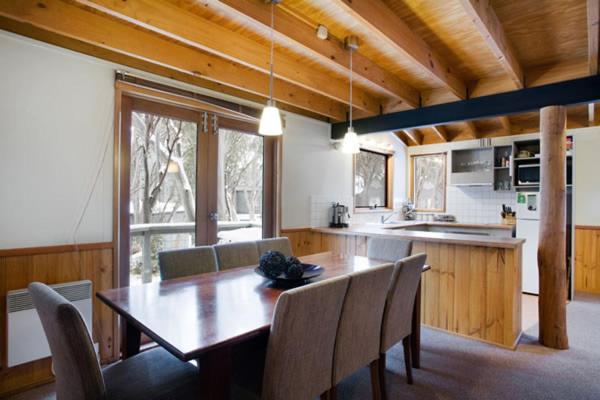 uma cozinha com uma grande mesa de madeira e cadeiras em Welkuminn em Dinner Plain