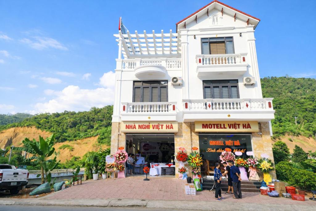 a white building with people standing in front of it at Việt Hà Motel in Bảo Lạc