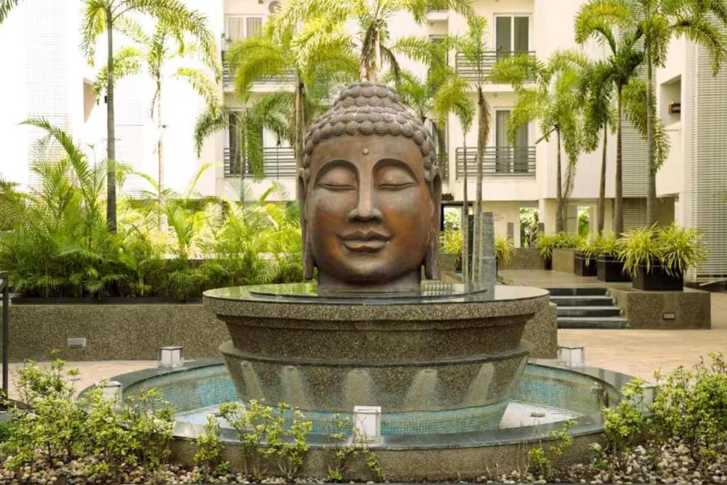a statue in a fountain in front of a building at Palm Suite With Sky Terrace Penthouse 11th Floor in Rajkot