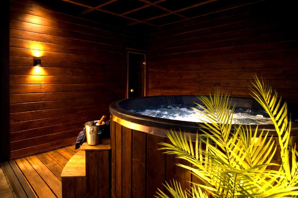 a hot tub in a wooden room with a plant at Prestige House Jacuzzi & Sauna in Gdańsk