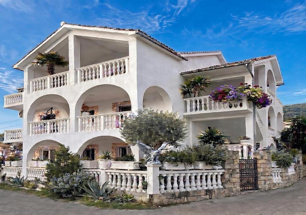 a large white house with potted plants on it at Apartmani Tamara in Tivat