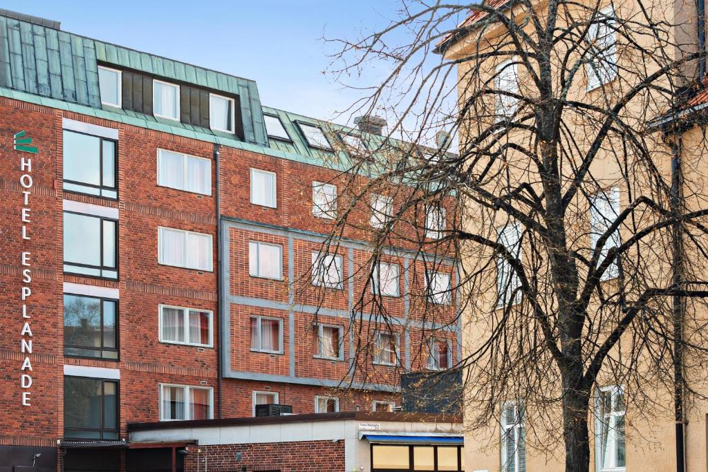 a red brick building with a tree in front of it at Best Western Hotel Esplanade in Västerås