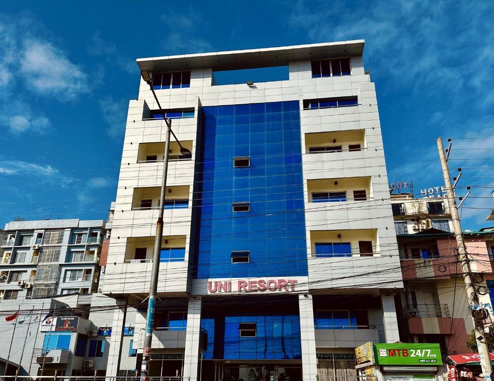 a tall white building with a blue at Uni Resort in Cox's Bazar