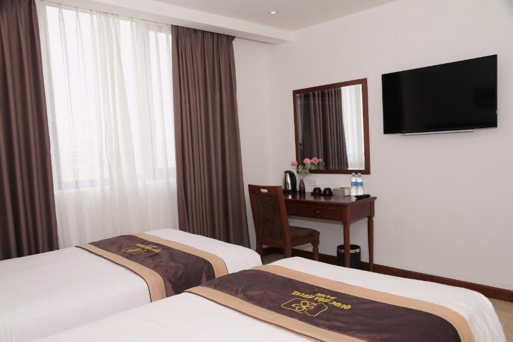 a hotel room with two beds and a desk at Ruby hotel Tuần Châu in Ha Long