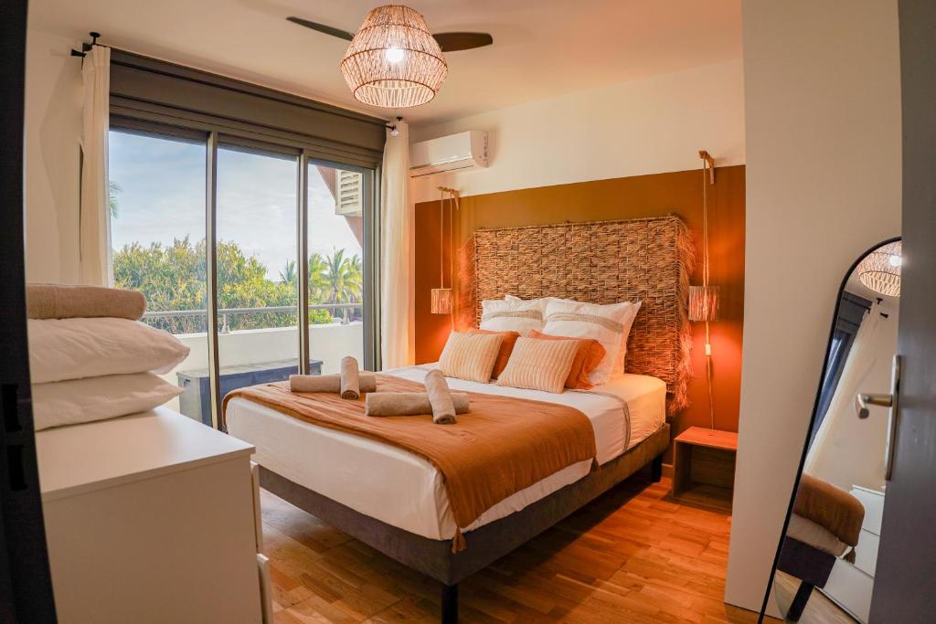 a bedroom with a large bed with a large window at T2 Ocean Cottage avec terrasse - 50m de la plage in Étang-Salé