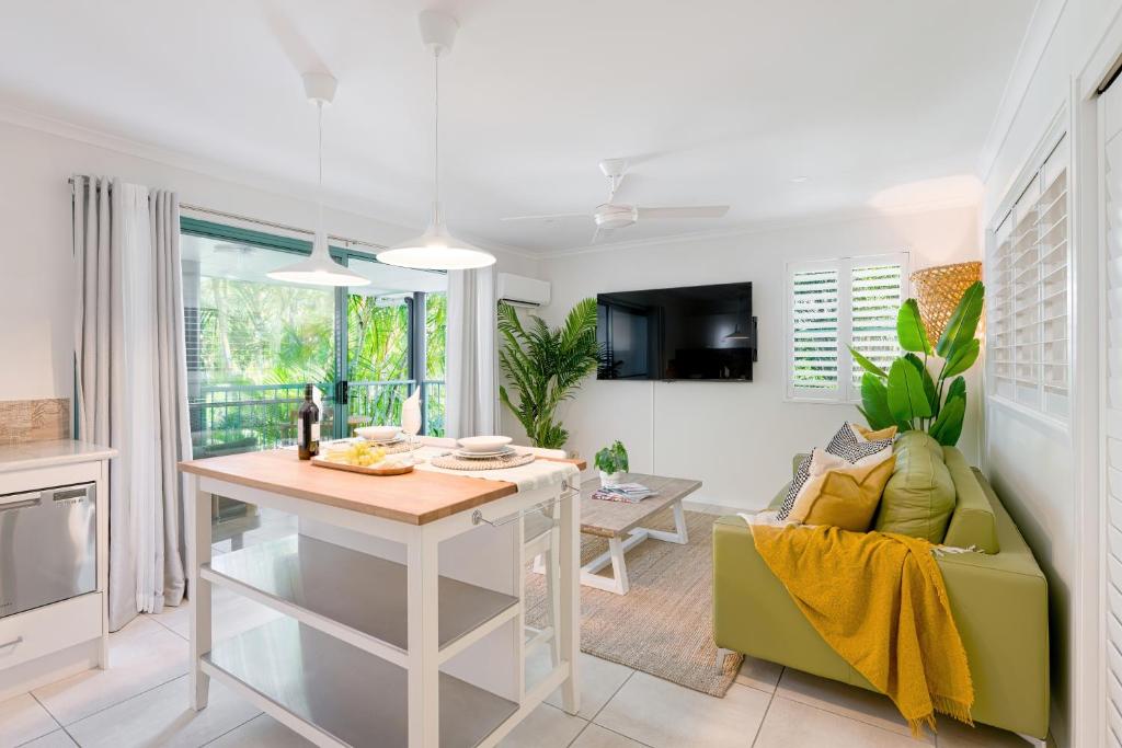 a kitchen and living room with a table and a couch at Chez Noosa Holiday Apartments in Sunshine Beach