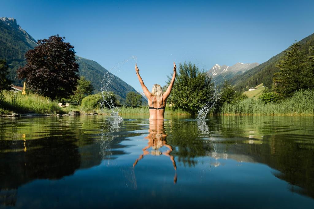 Eine Frau steht im Wasser eines Sees in der Unterkunft Forster's Naturresort in Neustift im Stubaital