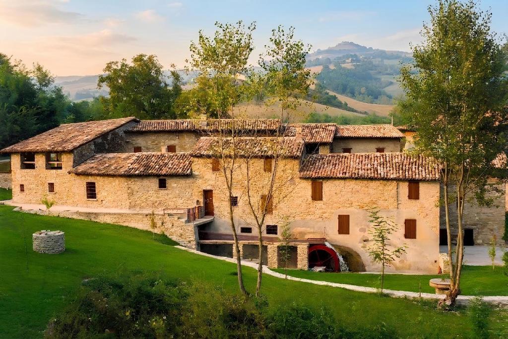 an old stone house in a green field at Mulino del Lentino in Nibbiano