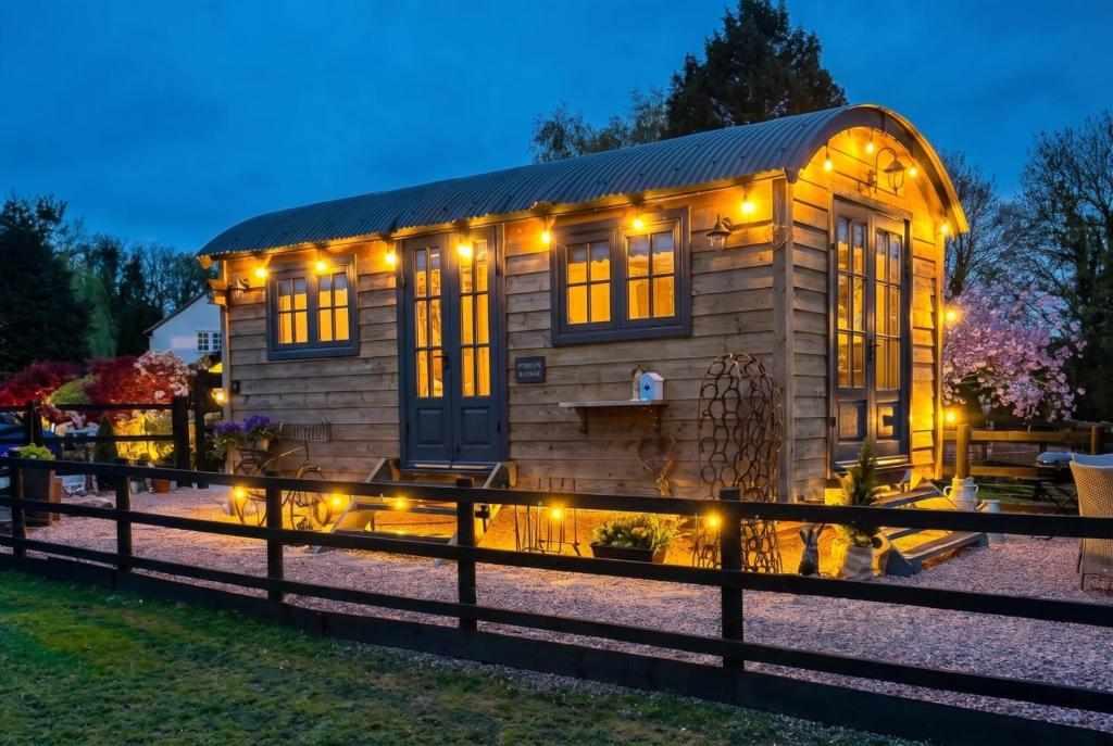 a small wooden house with lights on it at Secluded Countryside Shepherd's Hut on Working Farm near Audley in Audley
