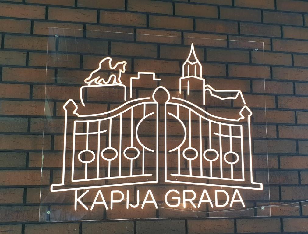 a metal sign on a brick wall with a gate at Kapija Grada in Ečka