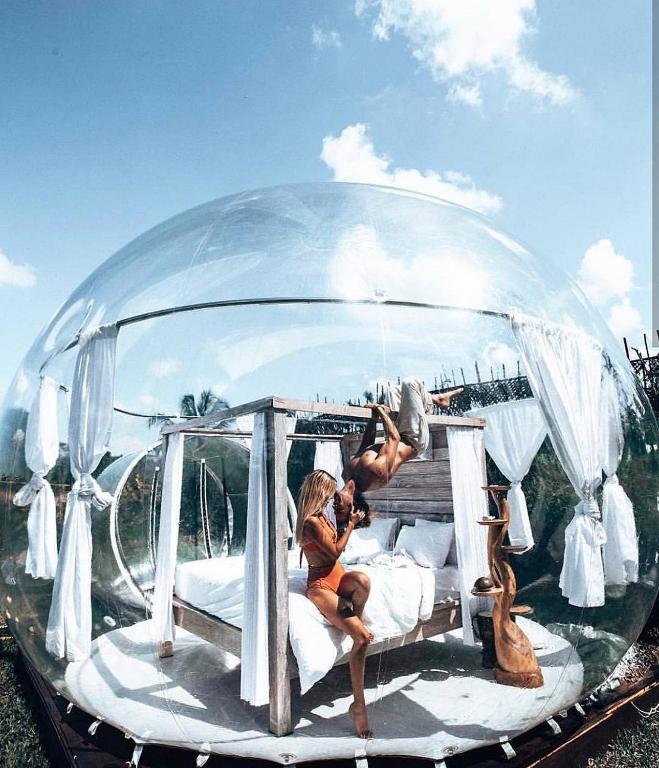 a couple sitting on a bed in a glass dome at Bubble 4 - Romantic With Bath Uluwatu in Uluwatu