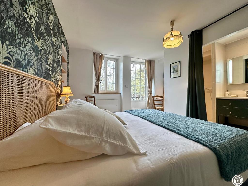 a bedroom with a large white bed with a blue blanket at Le Bief in Pont-et-Massène