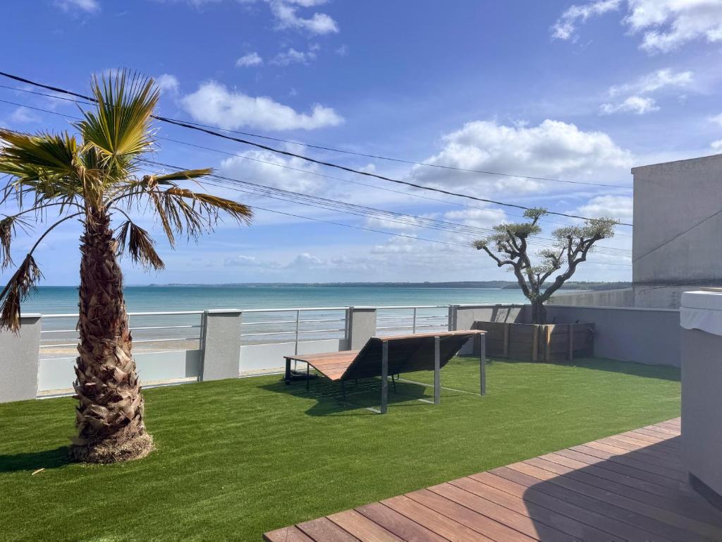 a balcony with a bench and a view of the ocean at Beach house Maison de plage les pieds dans l eau in Plérin