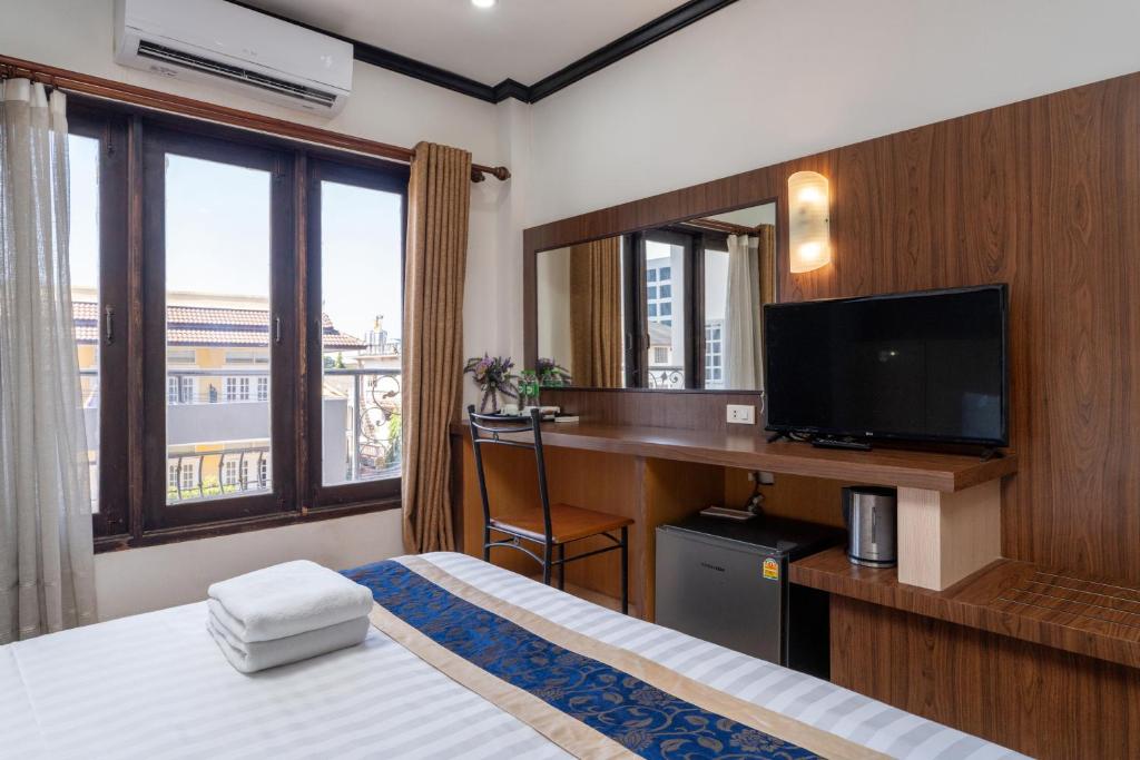 a hotel room with a bed and a desk with a television at Lucky city hotel in Vientiane