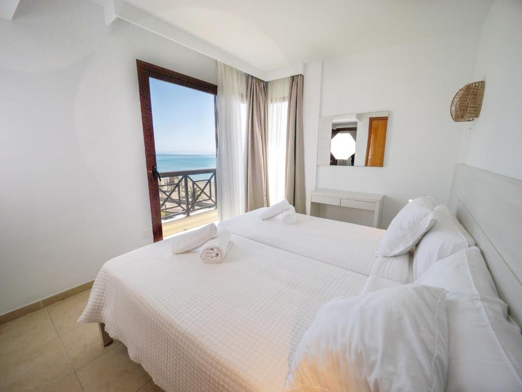 a bedroom with two beds and a view of the ocean at Prope Mare Apartamentos in Cala Millor