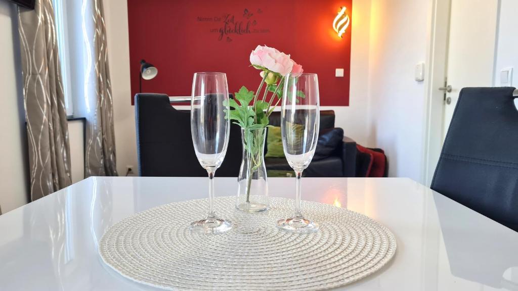 two wine glasses and a vase with a flower on a table at PONTUS Ferienwohnung FeWo 1 in Zislow