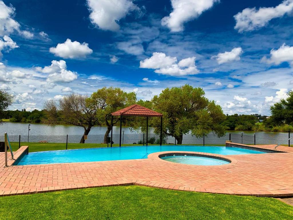 a swimming pool with a gazebo next to a lake at Lekoa Lifestyle Apartment in Vanderbijlpark