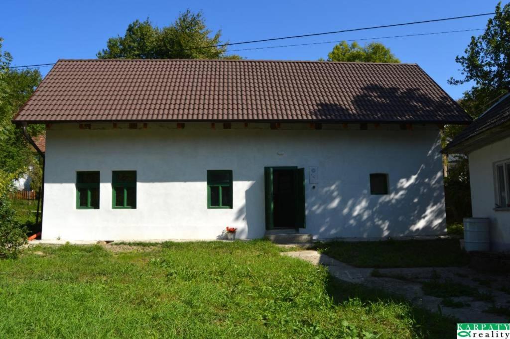 a white house with a red roof and green windows at Chalúpka na Podkylave in Podkylava