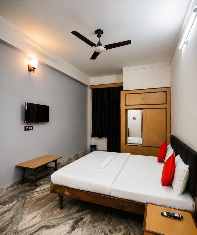 a bedroom with a bed and a ceiling fan at Hotel Ramya Palace in Gwalior