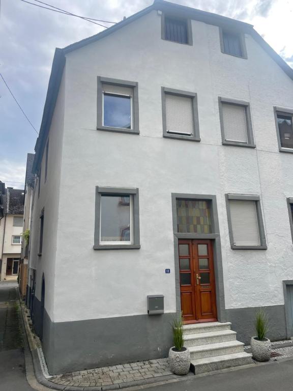 a white house with a red door on a street at Haus Janne in Zell an der Mosel