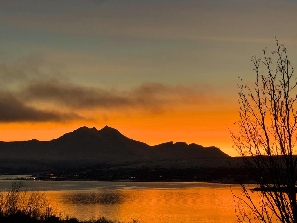 a sunset over a lake with a mountain in the background at Exclusive Northernlight villa at Sørtromsøya in Tromsø